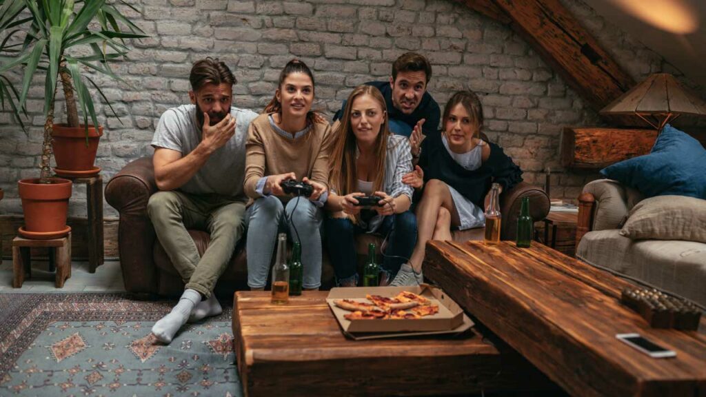 Amigos jugando videojuegos y comiendo pizza en Ambiente Corona
