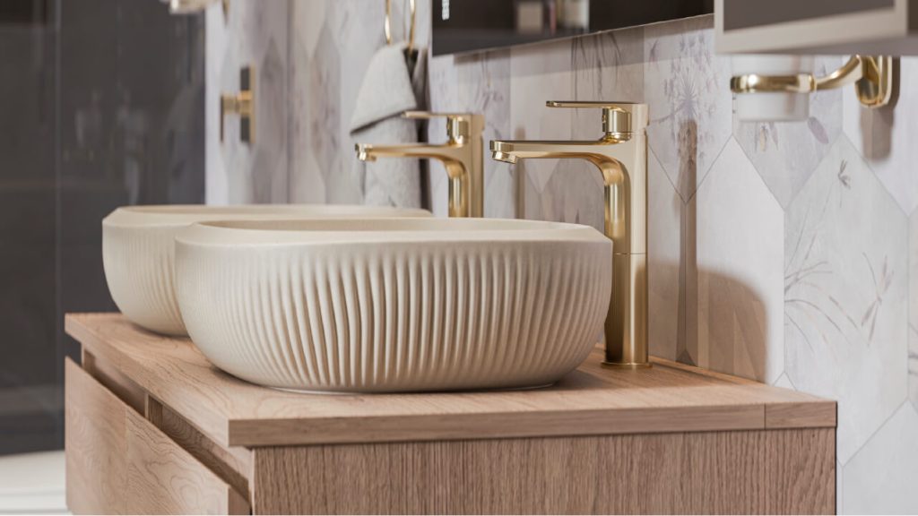 Ambiente baño Corona con lavamanos Cascade con textura ranurada y grifería Greta dorada.
