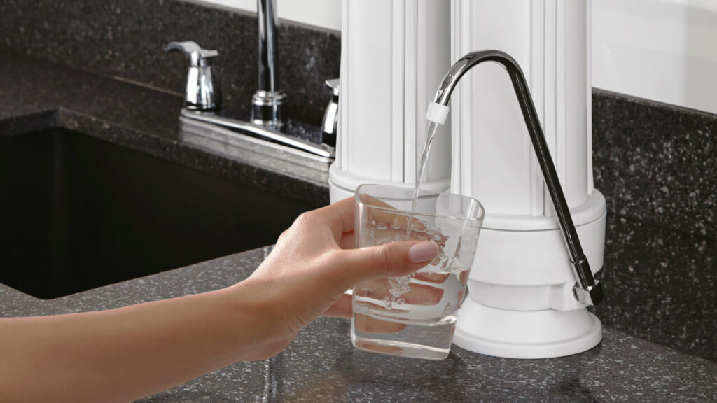 Mujer llenando agua con filtro Grival sobre mesón etapa 2